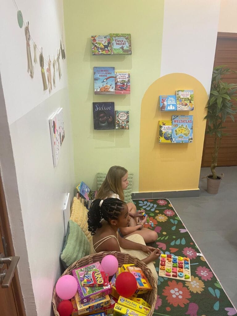 Children playing on the rug in the reading corner of the German classroom