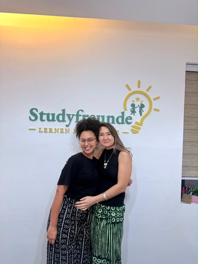 Two women in front of the Studyfreunde logo at the German language school in Accra