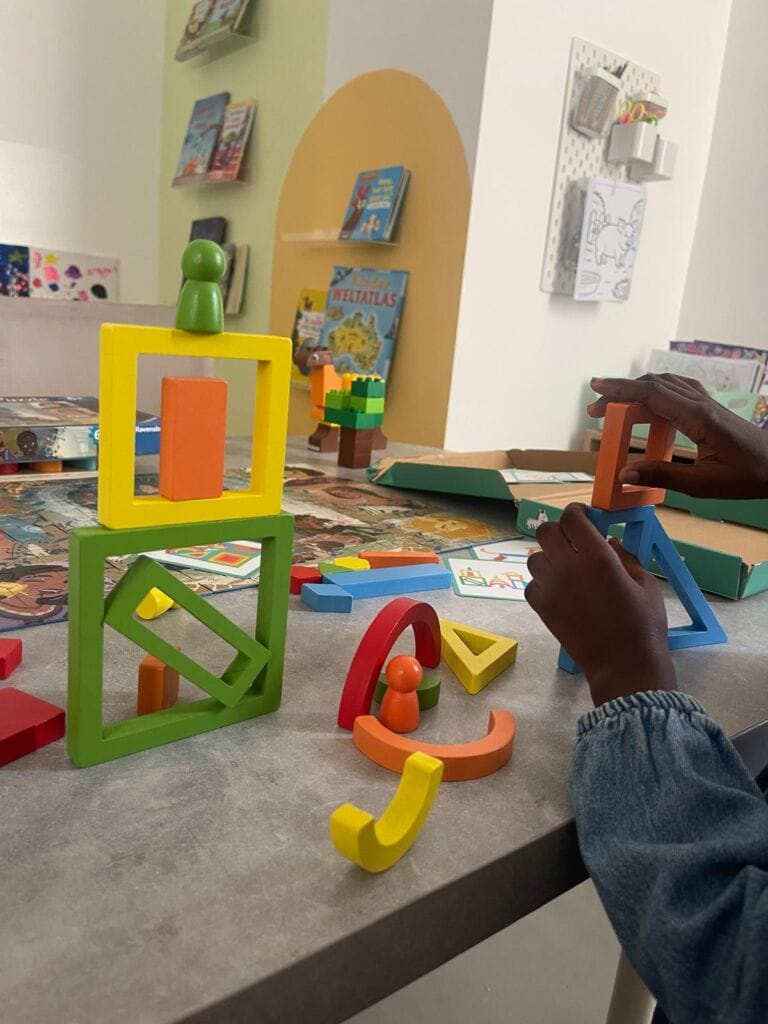 A preschool child playing with wooden shapes and colours in a German lesson at Studyfreunde in Accra