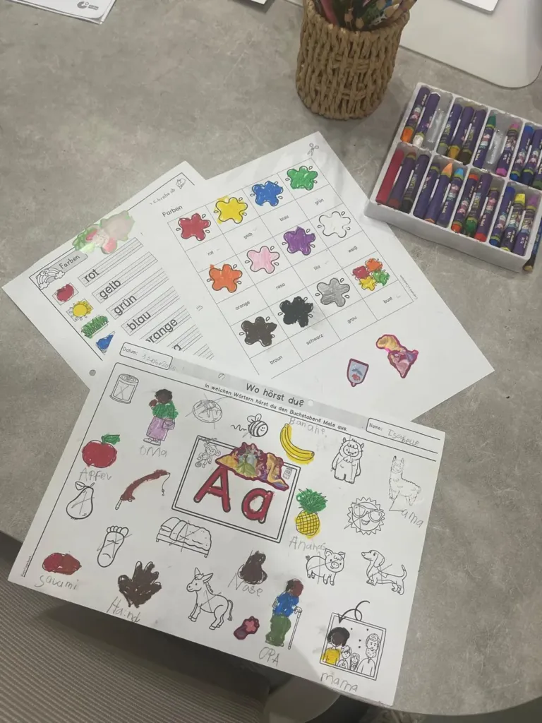 Colourful German first-words worksheets laid out on a table at Studyfreunde in Accra