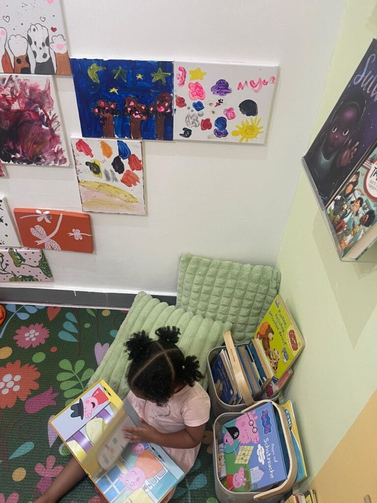 Reading corner with children's artwork on the wall and picture books on the floor
