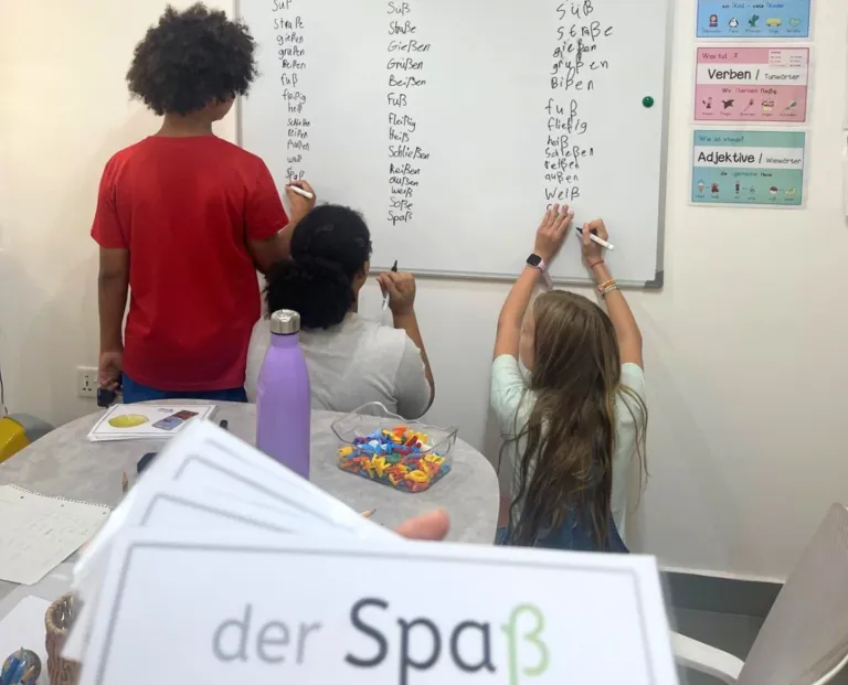 Free German trial lesson in Accra: three children writing German words on the board at Studyfreunde