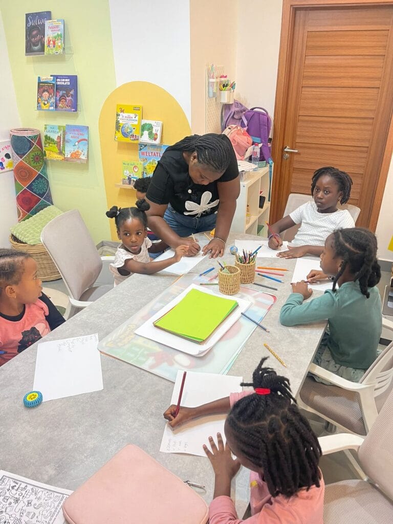 Studyfreunde teacher helping children at the table in the learning room in Accra