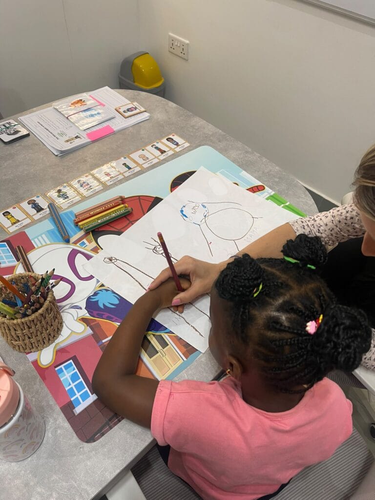 A preschool child drawing her family and learning the German family words with her teacher at Studyfreunde in Accra