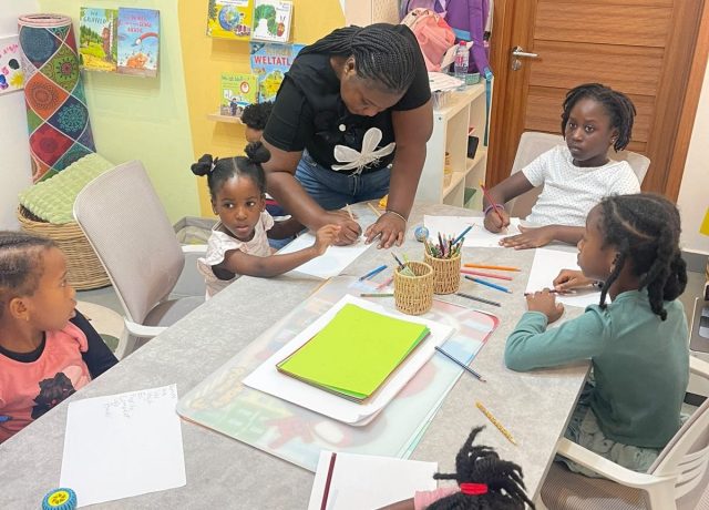Studyfreunde teacher helping children at the table in the learning room in Accra